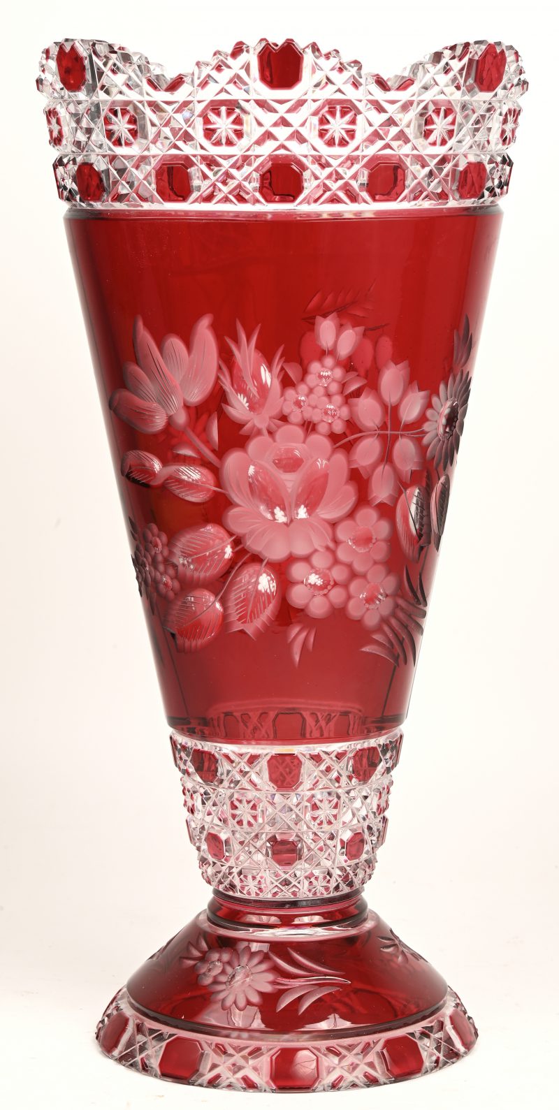 Een grote vaas van geslepen en rood gedubbeld kristal, versierd met een bloemendecor.