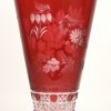 Een grote vaas van geslepen en rood gedubbeld kristal, versierd met een bloemendecor.