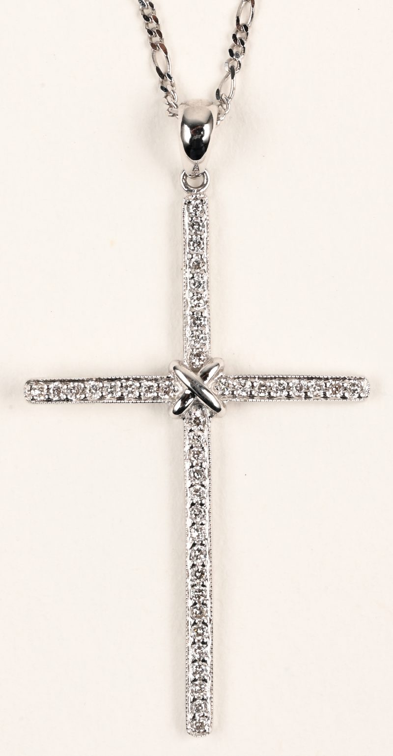 Een 18 K witgouden ketting met hanger in de vorm van een kruis bezet met briljanten met een gezamenlijk gewicht van +- 0,24 ct.