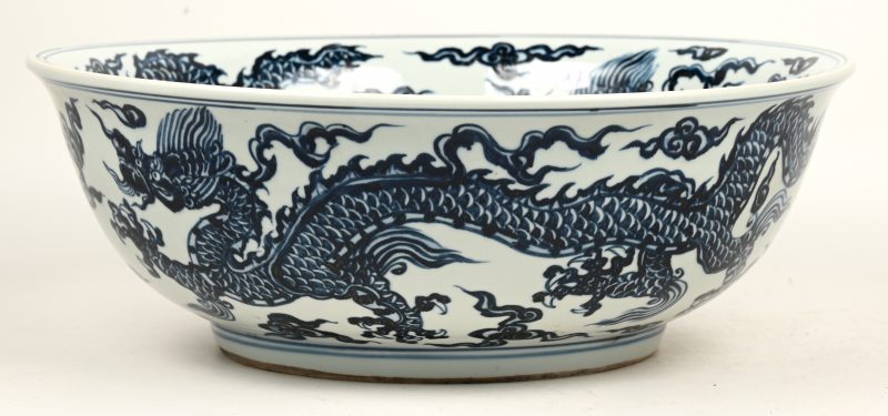 Een grote kom van blauw en wit Chinees porselein met een decor van draken.