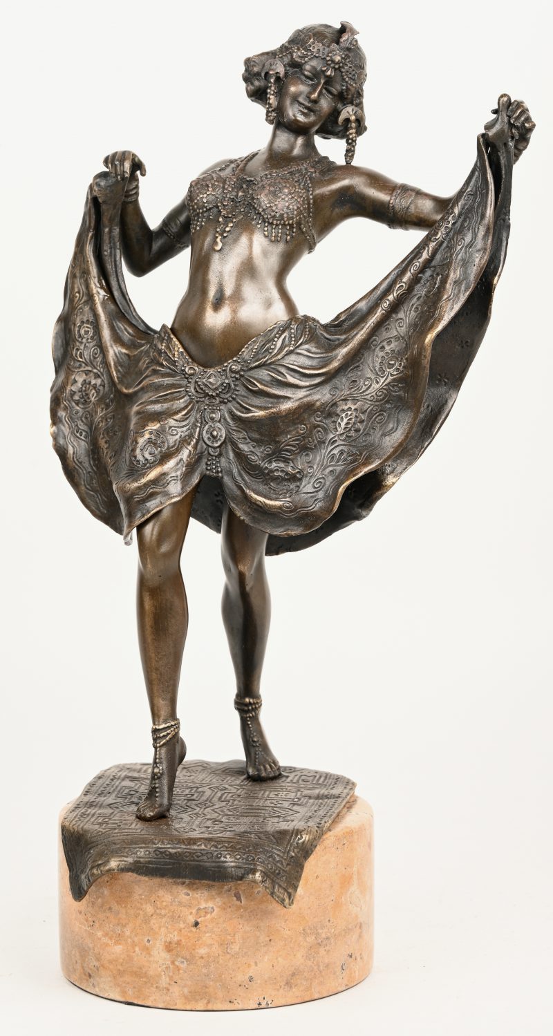Een bronzen art deco danseresje met openklappende rok. Op marmeren sokkel.