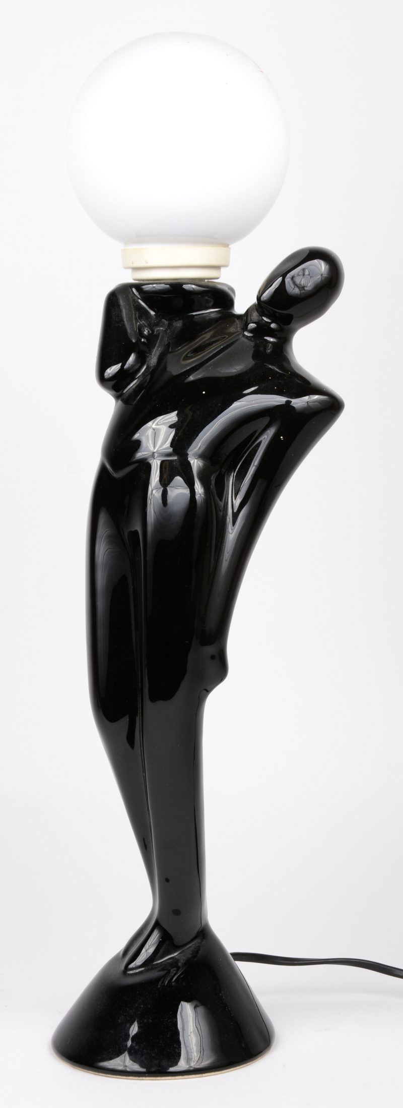 Een zwart geglazuurd aardewerken lamp in de vorm van een mannenfiguur.