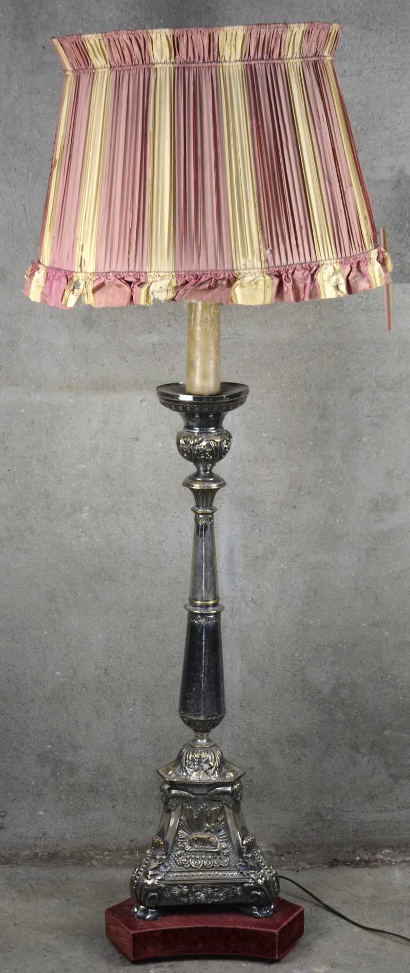Een staande lamp, gebaseerd op een verzilverd messingen barokke kerkkandelaar met gedreven voorstellingen van de Madonna met Christus en het Lam Gods.