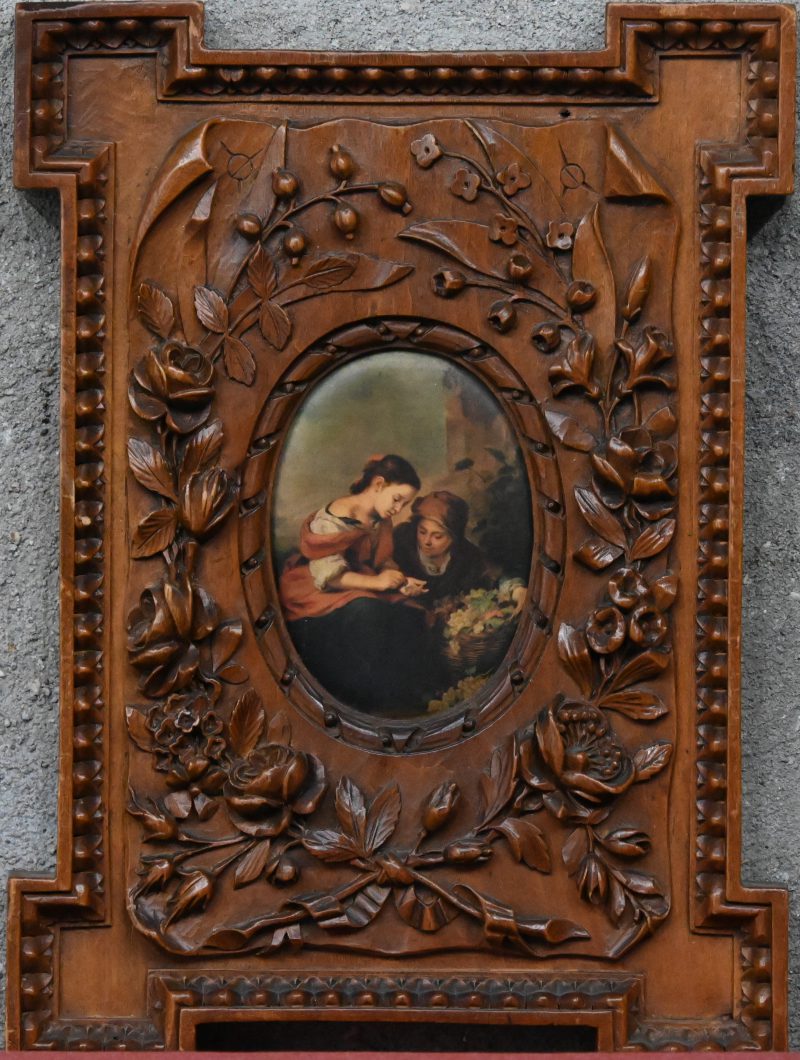 Een houten lijstje, versierd met fijn uitgestoken bloemen, bladeren en vruchten in reliëf.