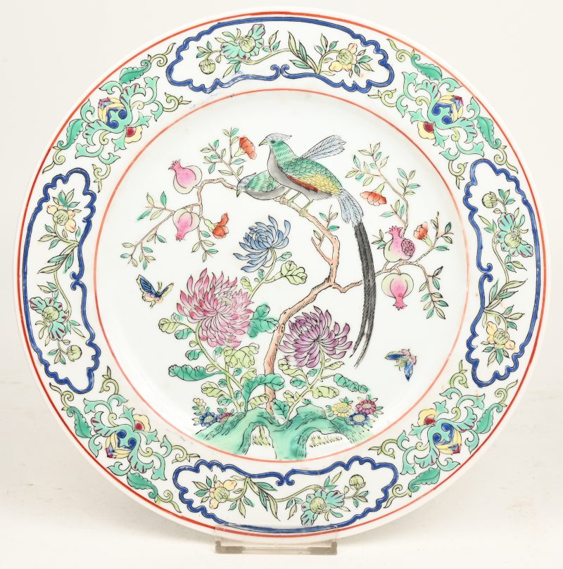 Een sierbord van Chinees porselein met meerkleurig decor van een vogel en vlinders in bloeiende struiken.