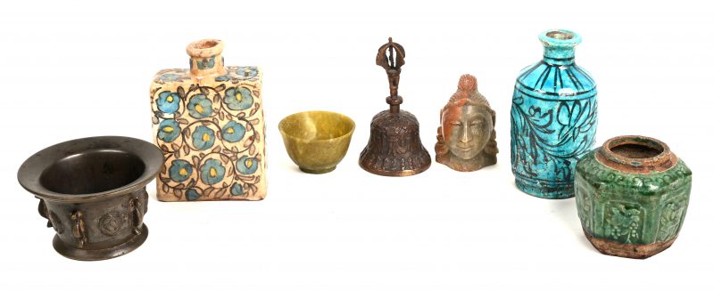 Een gevarieerd lot bestaande uit een antieke bronzen vijzel (gaatje), een Indisch bronzen vajrabelletje, een Boedhahoofdje van speksteen, een kopje van jadeïet, een Chinees potje van groengeglazuurd steengoed met reliëfdecor, een aardewerken theebus met een Perzisch motief, een Chinees vaasje van aardewerk, versierdin zwart op lichtblauwe fond.