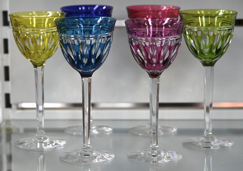 Acht geslepen kristallen wijnglazen op voet in verschillende kleuren.