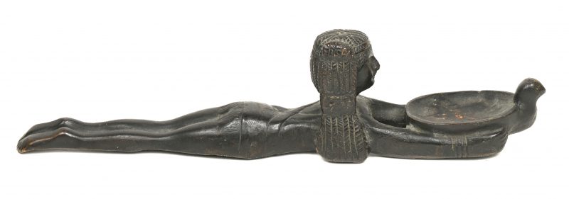 Een metalen beeldje van een liggende Egyptische met een schaal.