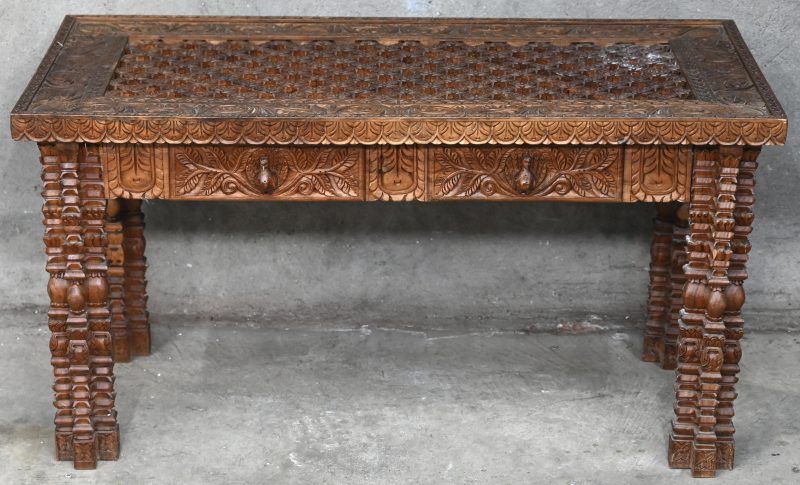 Een rechthoekige salontafel van gebeeldhouwd exotisch hout met opengewerkt blad en met twee laden. Indisch werk.