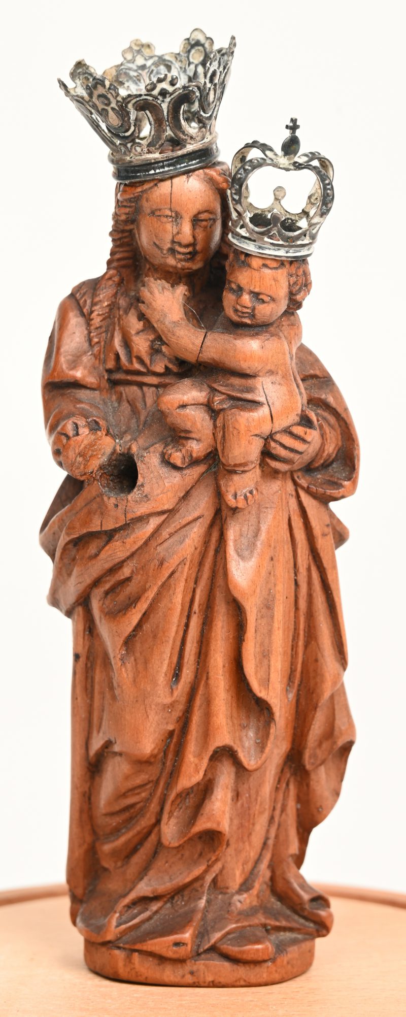 Een Madonna met Kind in gesculpteerd palmhout. Duits, 16de eeuw. Onder stolp, bijgevoegd twee metalen kroontjes. Hand manco.