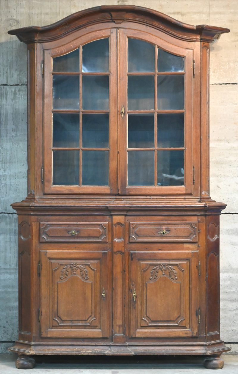 Tweedelige kast van gebeeldhouwd eikenhout. Onderaan twee deuren en twee laden, bovenaan twee beglaasde deuren. Luik, XVIIIde eeuw.
