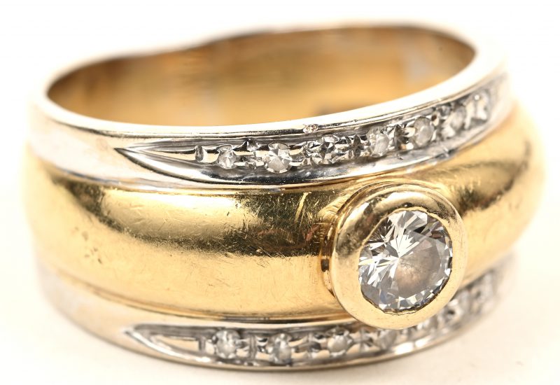 Een 18 karaats wit en geelgouden ring bezet met een centrale briljant van +- 0,25 ct. en kleine briljantjes.