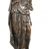 Een driedelig klokstel van brons en zwart marmer. De pendule versierd met een beeld van een spinnende jonge vrouw, de kandelaars in de vorm van kruikdraagsters naar Grieks voorbeeld. Goede staat, met slinger en sleutel. Frankrijk, XIXde eeuw.