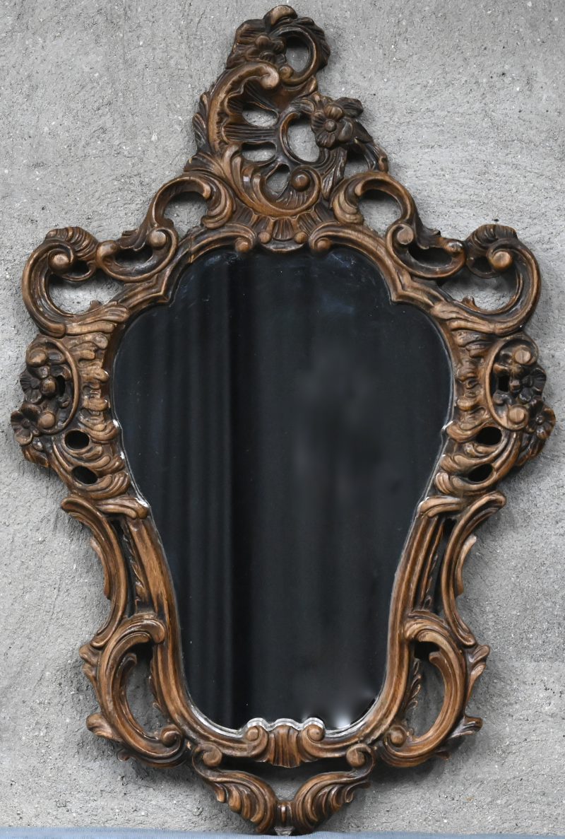 Een spiegel met gesculpteerd houten lijst.