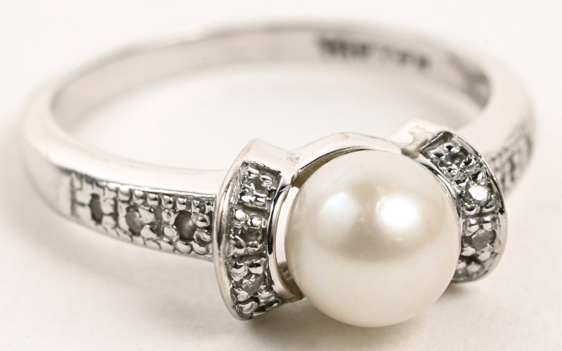 Een 18 karaats witgouden ring bezet met kleine briljantjes en een parel.