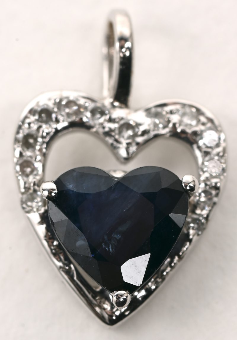 Een 18 karaats witgouden hanger bezet met kleine diamantjes en een hartvormige saffier van +- 0,25 ct.
