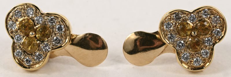 Een paar 18 karaats geelgouden oorbellen bezet met briljantjes met een gezamenlijk gewicht van +- 0,30 ct. en gele saffieren met een gezamenlijk gewicht van +- 0,30 ct.