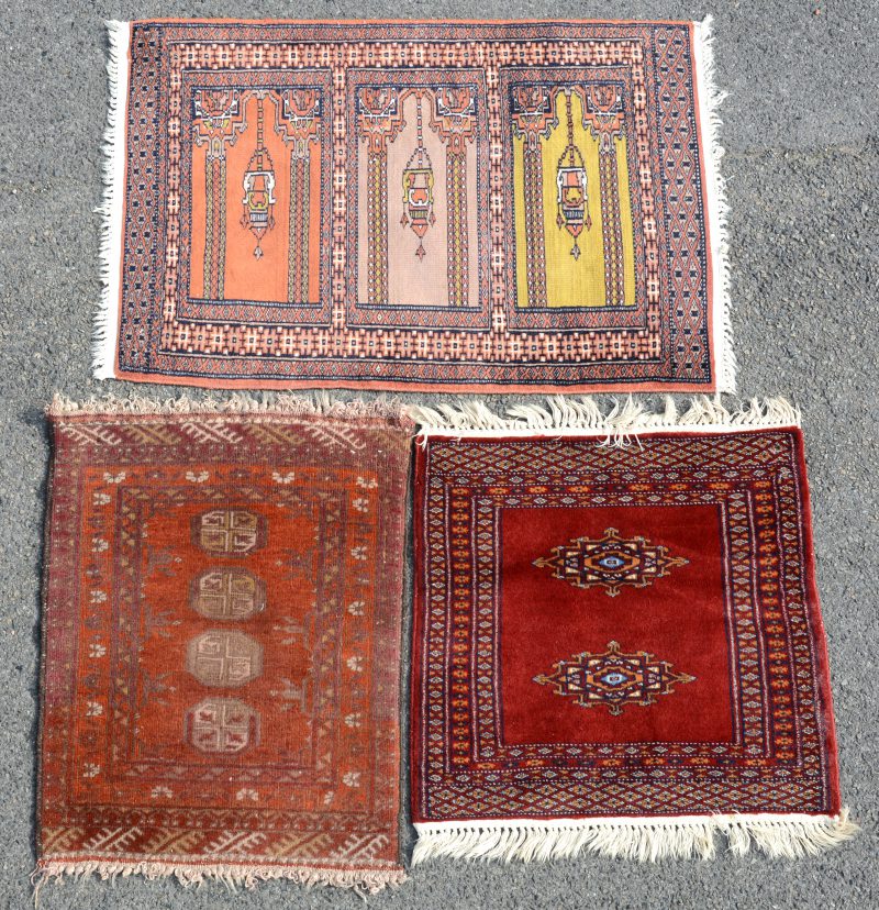 Een lot van drie kleine handgeknoopte Oosterse wollen tapijtjes, waarbij een bidkleedje (met lichte slijtage).
