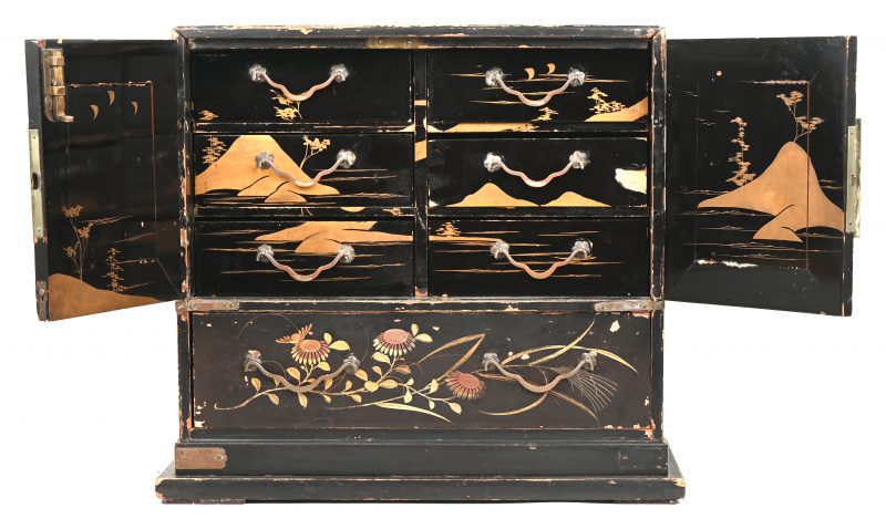 Een Japans juwelencabinetje met lakwerk en met geelkoperen beslag. Onderaan een lade, waarboven twee deurtjes, die op hun beurt zes kleine laden verbergen. Slijtage. Begin XXste eeuw.