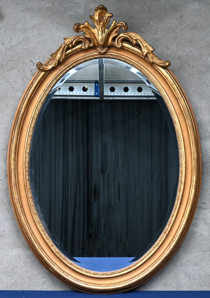 Grote spiegel in ovaal vorm, ornament bovenaan, verguld.