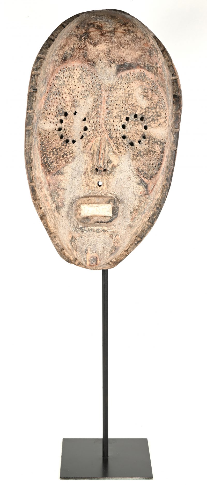 Een masker van gebeeldhouwd hout op staander.