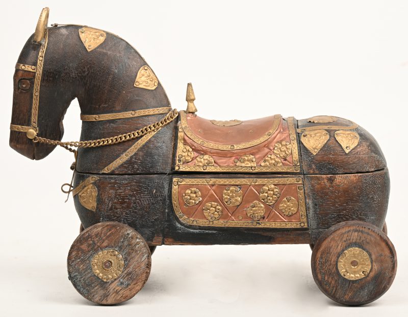 Een houten paard op wielen als doosje bezet met rood en geel koper.