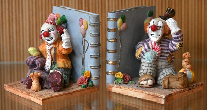 Een paar boekensteunen van biscuit in de vorm van clownen.