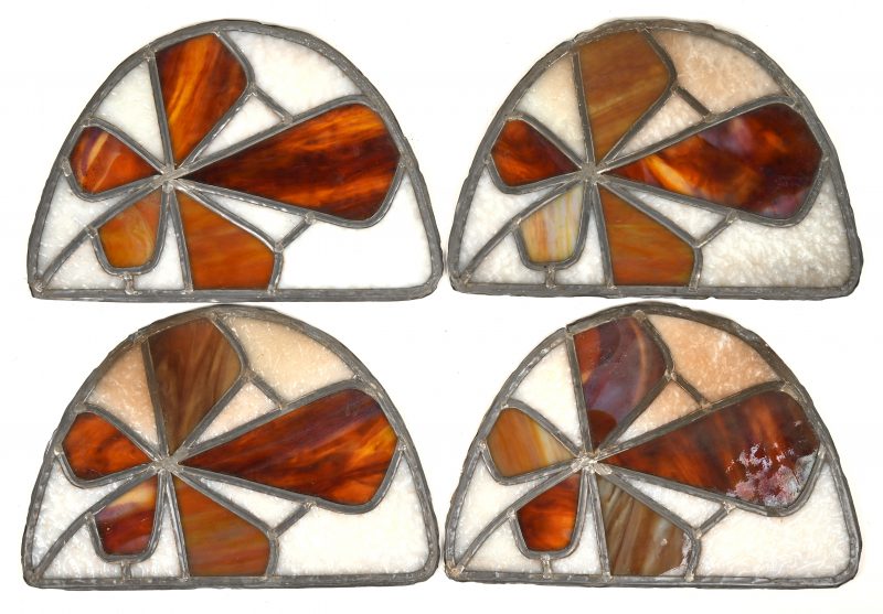 Vier kleine voorzet glasramen in de vorm van wilde kastanjebladeren.