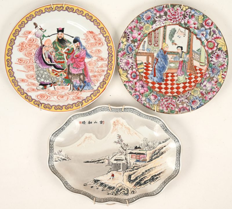 Een lot van 3 Aziatisch porseleinen sierborden, waarvan 2 ronde recent Famille Rose en 1 in ovalen schelpachtige vorm. Afgebeeld diverse kleuren en taferelen, onderaan gemarkeerd.