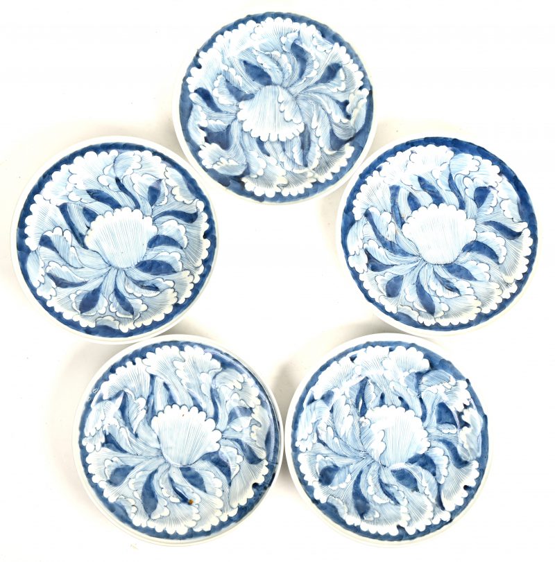 Een serie van vijf porseleinen borden met een blauw en wit bladmotief in reliëf. Chinees werk, onderaan gemerkt.