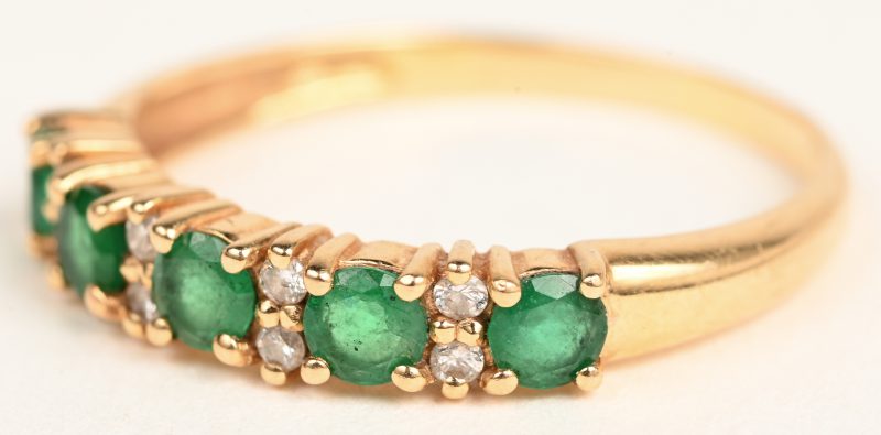 Een 18 karaats geelgouden ring bezet met smaragden met een gezamenlijk gewicht van +- 0,50 ct. en 8 kleine briljantjes.