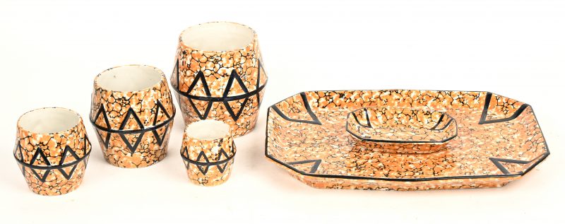 Een set van vier oranje polychroom aardewerken vaasjes met twee bijhorende plateaus. Eén schilfer aan het kleinste schaaltje.