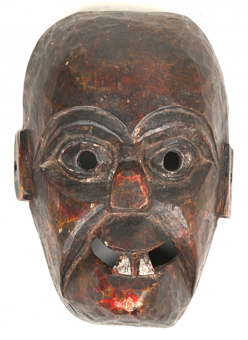 Een Aziatisch houten masker met sporen van polychromie.