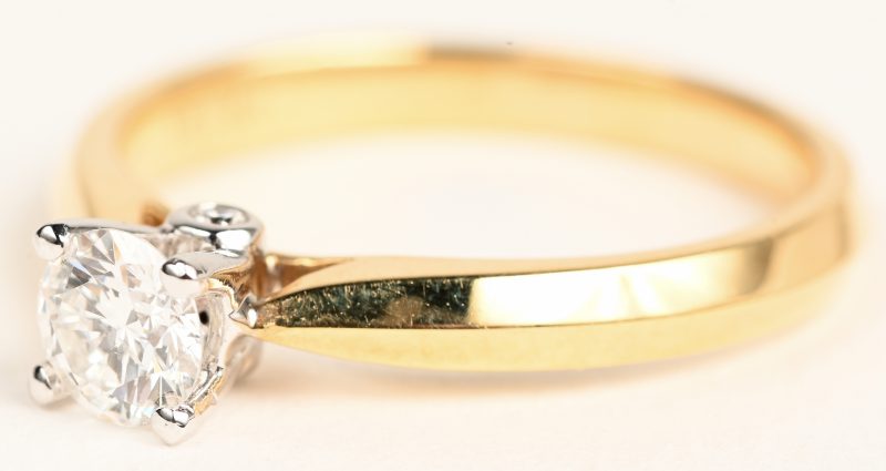 Een 18 karaats witgouden ring bezet met een centrale diamant van +- 0,34 ct. en twee kleine briljantjes van 0,02 ct. EVVS1.