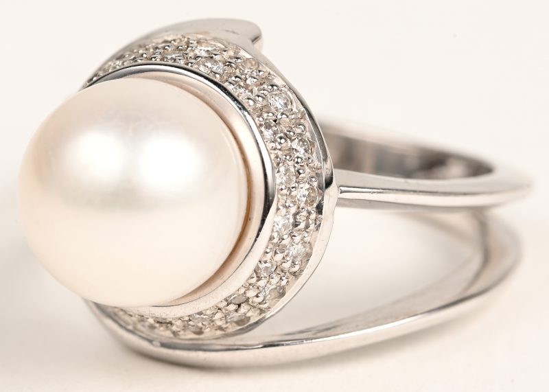 Een 18 karaatswit gouden ring bezet met briljanten met een gezamenlijk gewicht van +- 0,44 ct. en een parel.