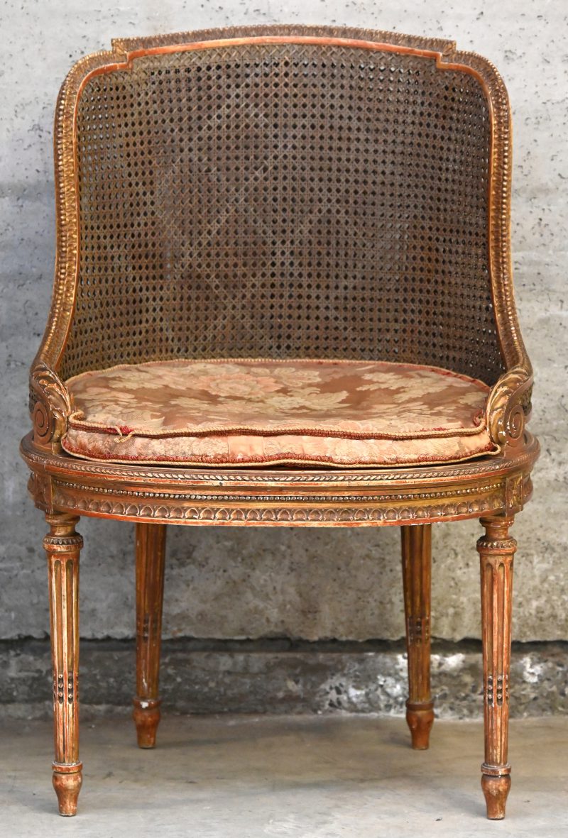 Een houten gesculpteerd en gepatineerd Louis XVI type bureaustoel. Met kussen en rieten zit-en rugleuning.