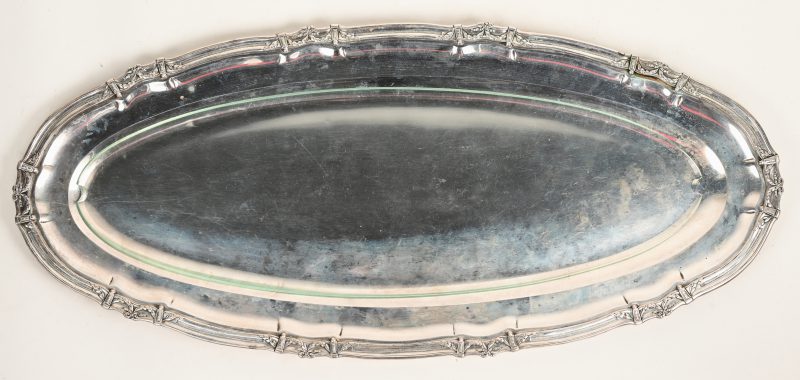 Een verzilverde ovale schotel met glazen inleg.