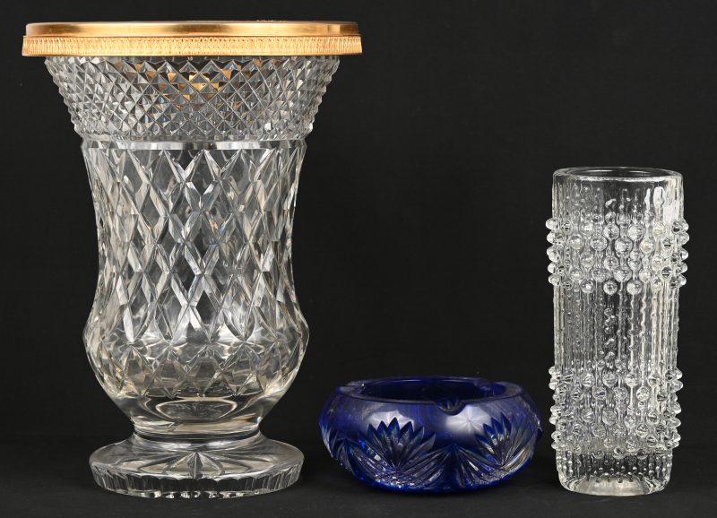 Drie stuks kristal en glaswerk, bestaande uit een kleurloze vaas op piedouche (randschade), een kleurloze Italiaans glazen vaas en een asbak van geslepen blauw Boheems kristal.