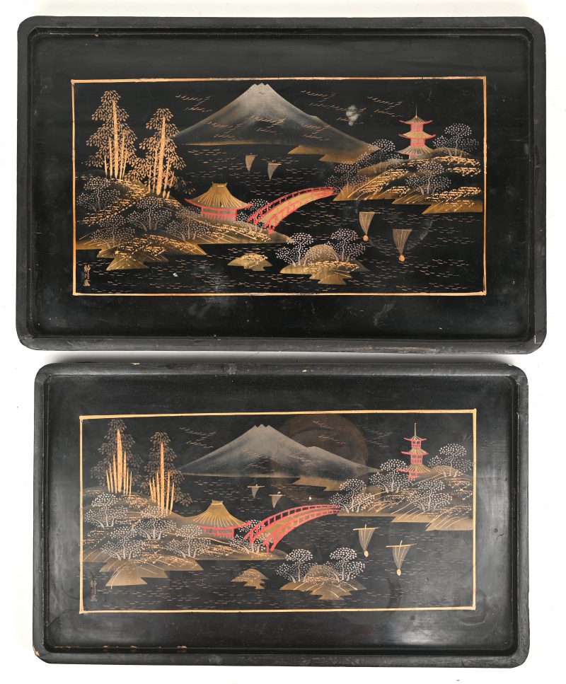 Twee in elkaar passende Japanse dienbladen van zwartgelakt hout met meerkleurige landschapsdecors.