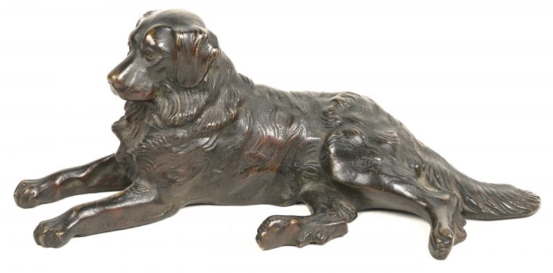 Een bronzen beeldje van een liggende hond.