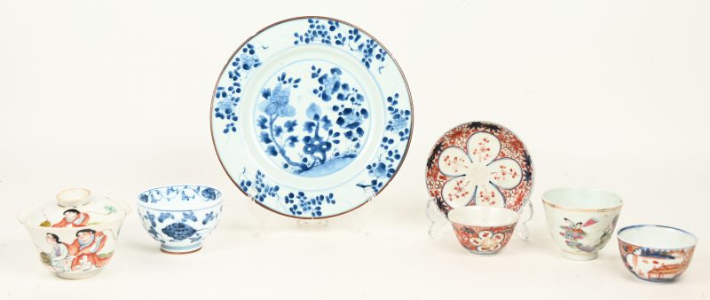 Lot Chinees en Japans porselein met drie theekopjes, waarvan één met deksel, een schoteltje en een blauw en wit dessertbord met decor van een bloeiende theeboom. XIXde eeuw.