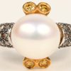 Een 18 karaats wit en geelgouden ring bezet met briljanten witte en gele met een gezamenlijk gewicht van +- 0,76 ct. en een parel.