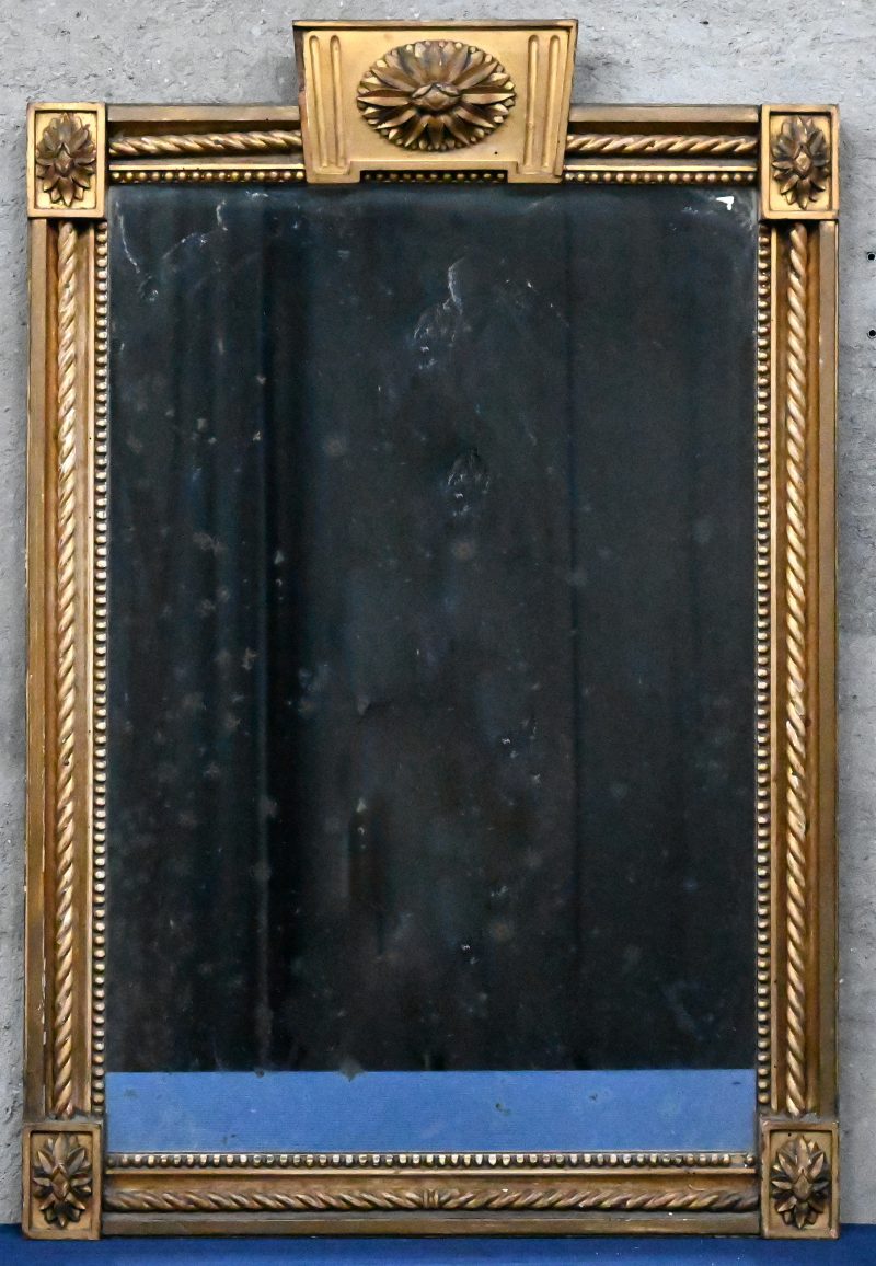 Een Louis XVI spiegel, met vergulde kader met ornamenten.