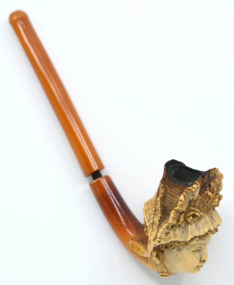 Een pijp met een meerschuimen kop in de vorm van ”une Alsacienne”. Amberkleurige steel.