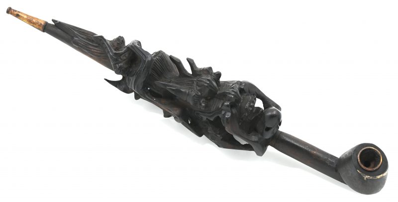 Een Chinese pijp met een effen kop en met een rijkelijke gebeeldhouwde steel in de vorm van een raak. Metalen mondstuk.