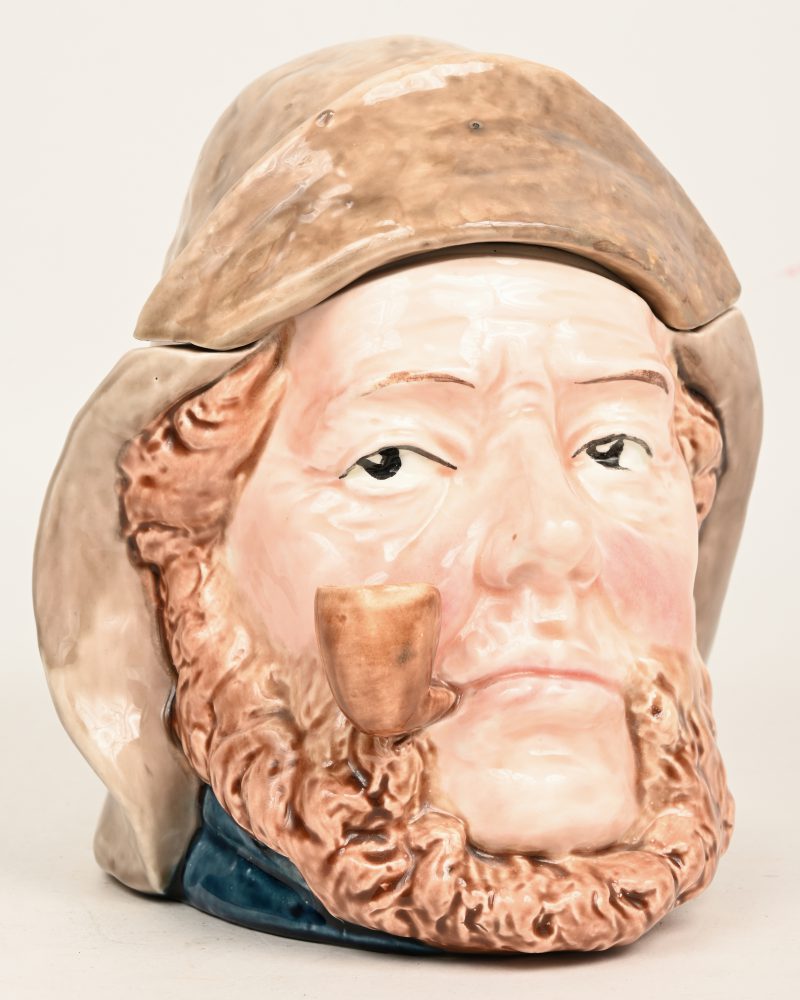 Een tabakspot van polychroom porselein in de vorm van de kop van een pijprokende zeeman.