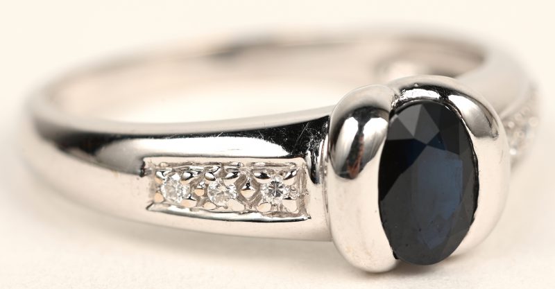 Een 18 karaats witgouden ring bezet met kleine briljantjes en een saffier van +- 0,40 ct.