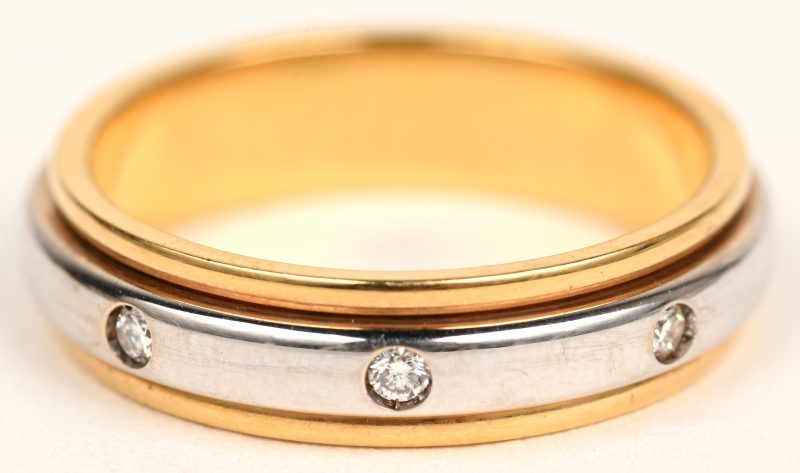 Een 18 karaats wit en geelgouden ring bezet met briljanten met een gezamenlijk gewicht van +- 0,16 ct. Met draaivorm.