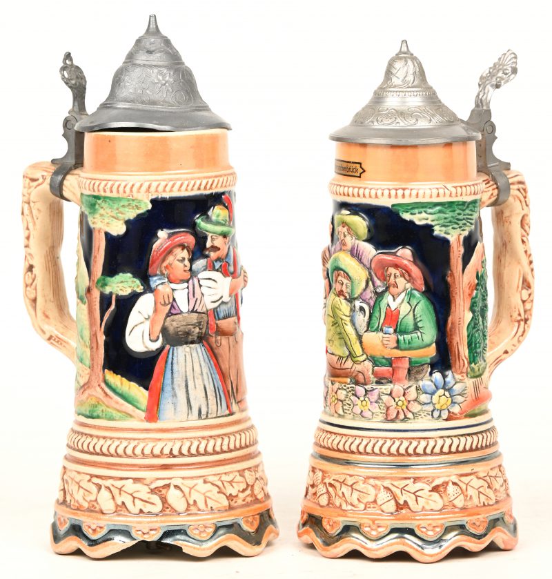 Een lot van 2 keramieken muziekdozen in drankbeker met tinnen klep. Decor in reliëf en opschrift “Echternacherbrück”.