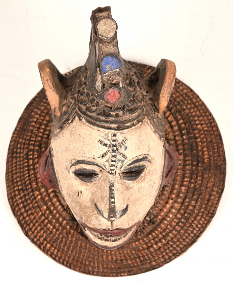 Een Afrikaans, in gepolychromeerd terracotta masker met vlechtwerk. Igbo, Nigeria.